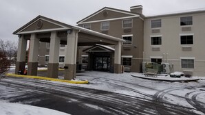 Um hotel com vários andares, entrada coberta e área de estacionamento.