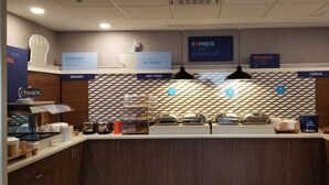 Espaço de café da manhã com áreas identificadas para padaria, comidas quentes e cereais.