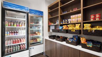 A refrigerated display with various beverages and snacks, including bottled water, sodas, and chips.