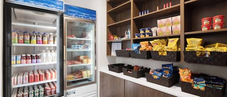 A refrigerated display with various beverages and snacks, including bottled water, sodas, and chips.