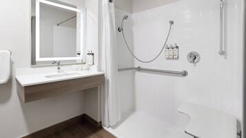 A modern bathroom with a shower, a sink with a mirror, and toiletries.