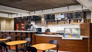 A modern restaurant with wooden tables and chairs, a bar area, and a menu board. - Courtyard by Marriott Scranton Montage Mountain (Moosic)