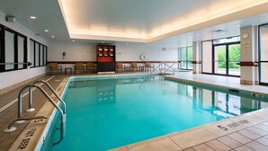 A swimming pool with clear water, surrounded by a tiled deck and a seating area with chairs. - Courtyard by Marriott Scranton Montage Mountain (Moosic)