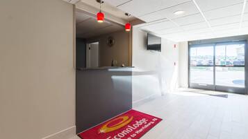 A hotel reception area with a red carpet mat, a reception desk, and a television mounted on the wall.