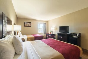 Une chambre d’hôtel avec deux lits, un bureau avec une chaise, une télévision et une fenêtre avec des rideaux.