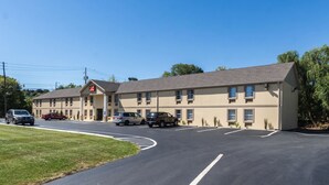 A motel with a parking lot, multiple vehicles parked, and a clear sky.