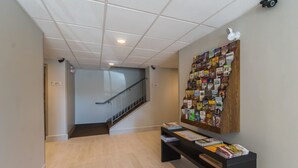 A hallway with a tiled floor, a staircase, and a wall-mounted book display. - Econo Lodge Harrisburg - Southwest of Hershey Area (Harrisburg)