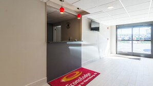 A hotel reception area with a red carpet, a reception desk, and a large window offering a view of the parking lot. - Econo Lodge Harrisburg - Southwest of Hershey Area (Harrisburg)