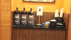 Un espace dédié au café, équipé de trois distributeurs étiquetés « eau chaude », « café décaféiné » et « café normal ».