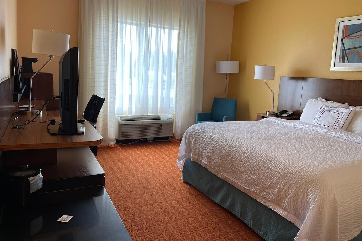 A hotel room with a bed, desk, computer, and two lamps.