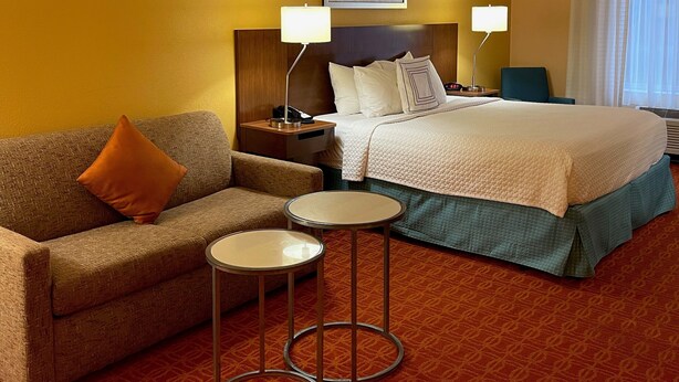 Une chambre d’hôtel avec un lit, un canapé, deux petites tables et une table de chevet.