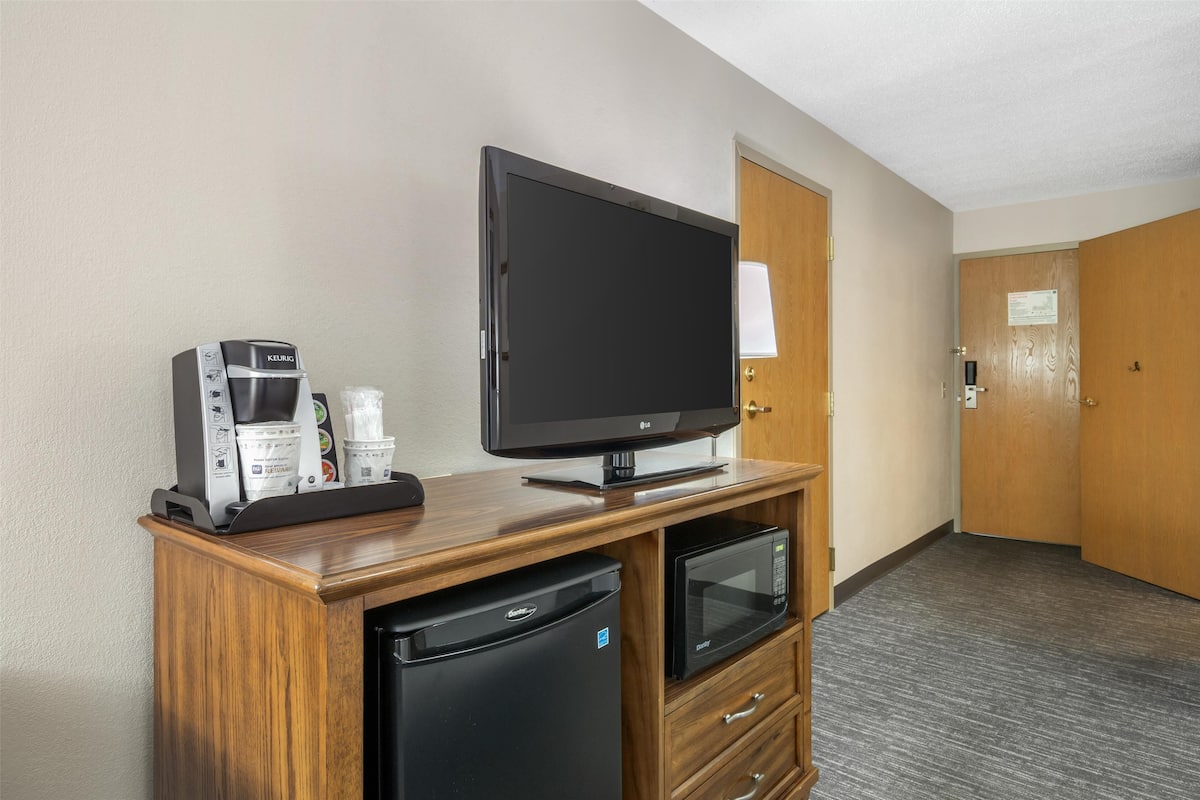 Une chambre d’hôtel équipée d’une télévision, d’une machine à café et d’un four à micro-ondes, le tout posé sur un meuble en bois.