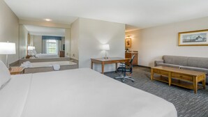 Een hotelkamer met een groot bed, een bureau met stoel, een bank en een kleine tafel.