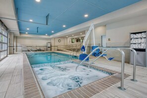 Una piscina interior con techo azul, un puesto de socorrista y un vestuario con toallas.