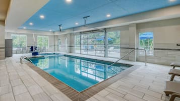 Een binnenzwembad, ligstoelen bij het zwembad