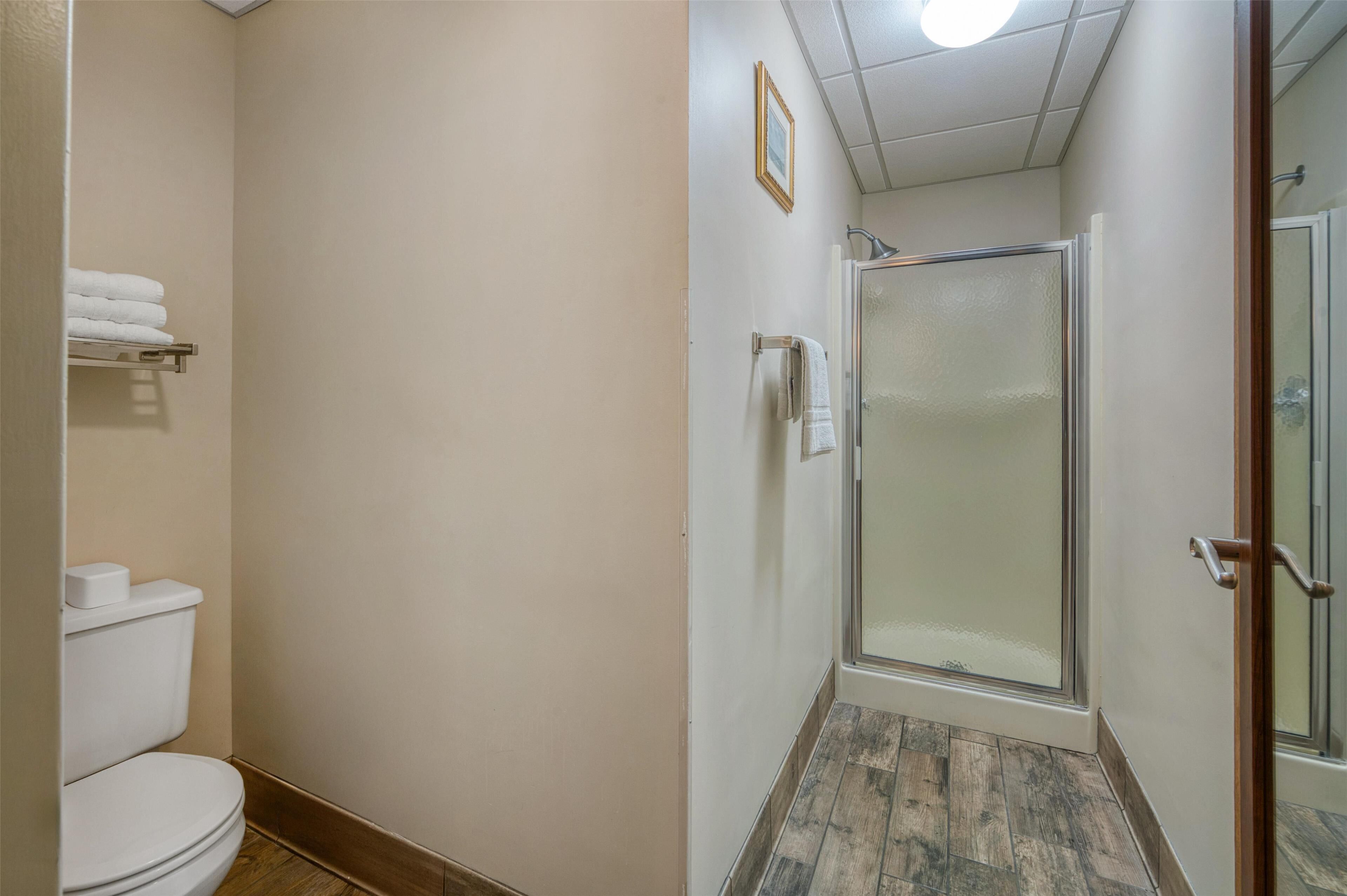 A bathroom with a toilet, a towel rack, and a shower with a glass door.