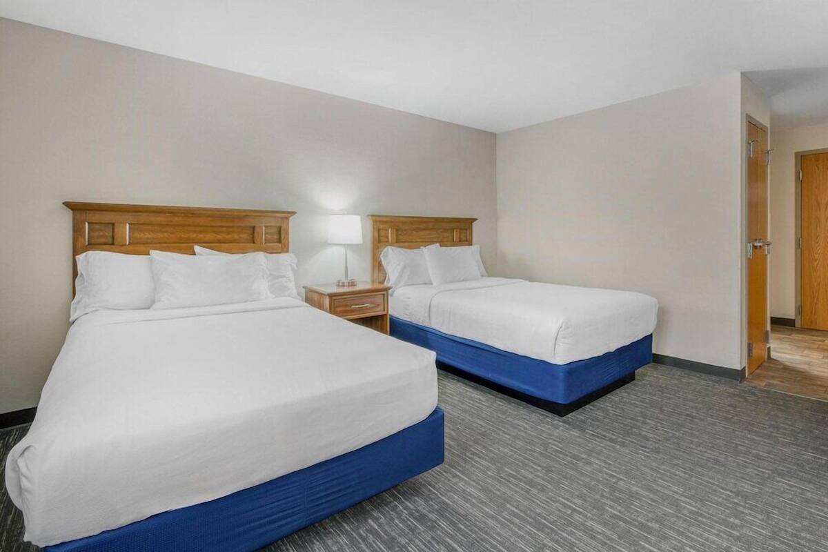 Una habitación de hotel con dos camas, una mesita de noche, una lámpara y una puerta.