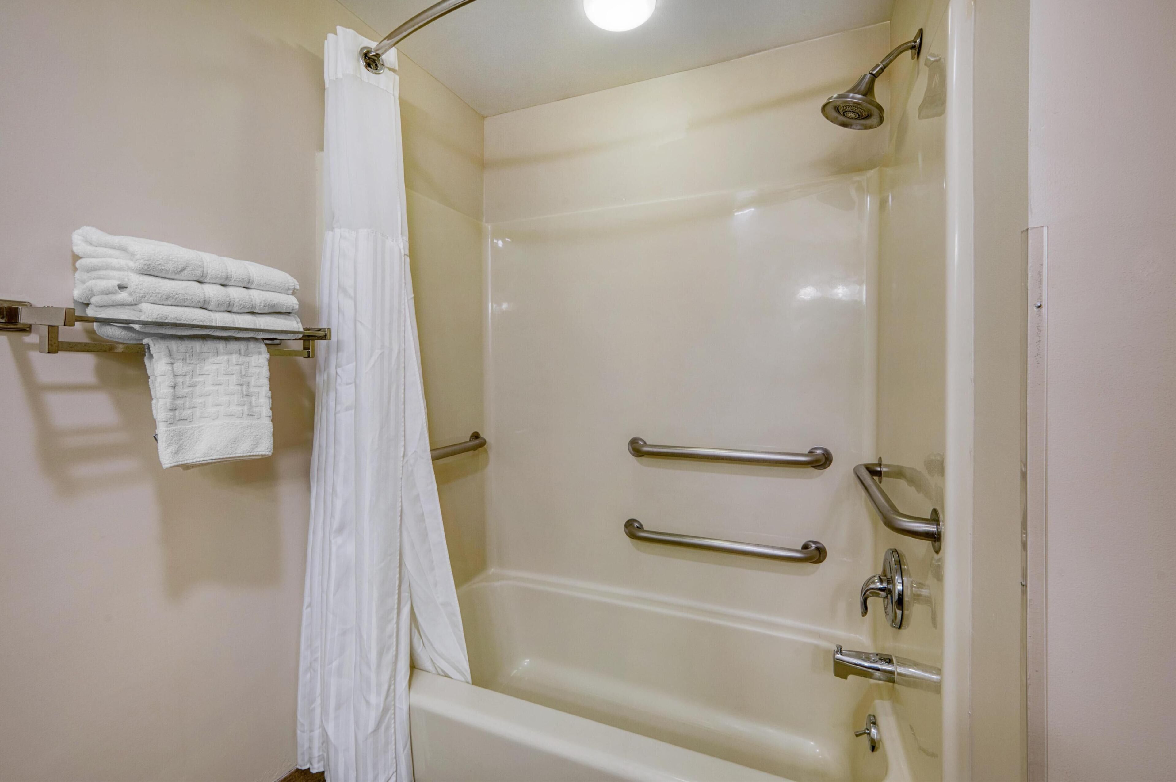 Ein Badezimmer mit einer Badewanne, einer Duschvorhang und einem Handtuchhalter mit gefalteten Handtüchern.