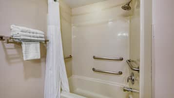 Ein Badezimmer mit einer Badewanne, einer Duschvorhang und einem Handtuchhalter mit gefalteten Handtüchern.