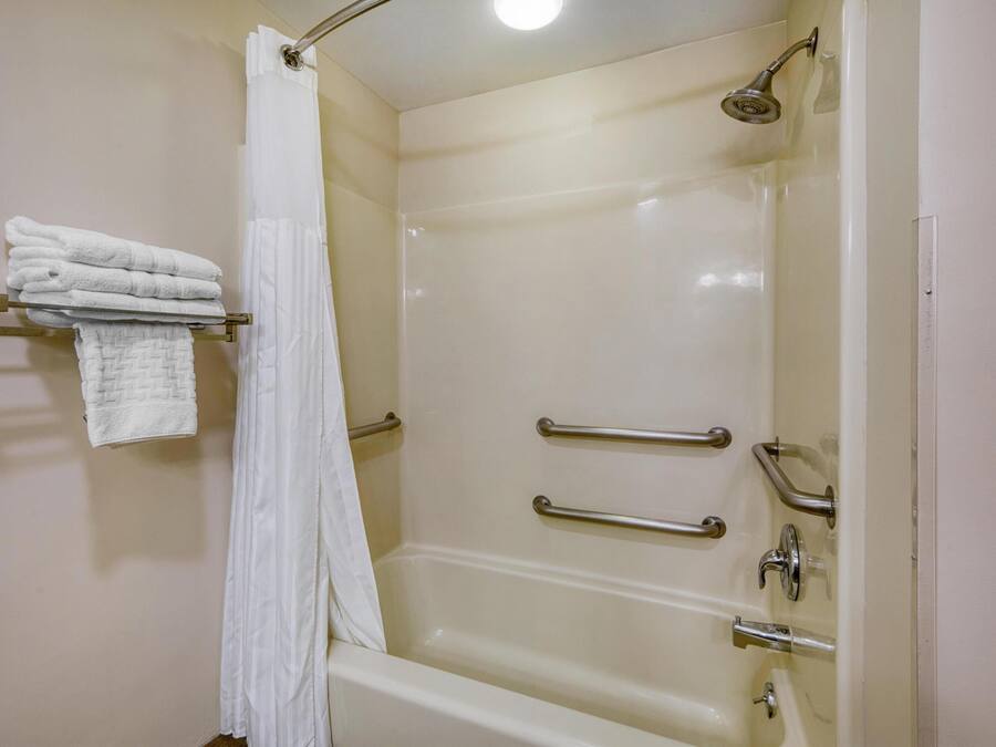 Ein Badezimmer mit einer Badewanne, einer Duschvorhang und einem Handtuchhalter mit gefalteten Handtüchern.