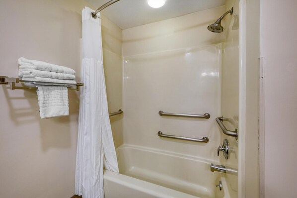 A bathroom with a bathtub, a shower curtain, and a towel rack with folded towels.