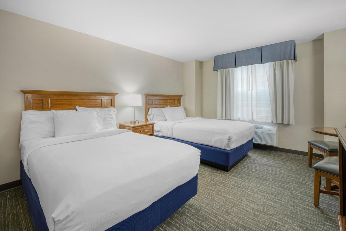 Une chambre d’hôtel avec deux lits, un bureau et une chaise.
