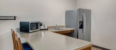 A compact kitchen with a microwave, coffee maker, and refrigerator.