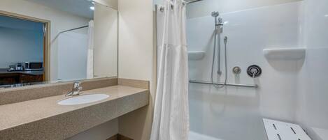 Uma casa de banho moderna com lavatório, espelho, chuveiro e porta de vidro.
