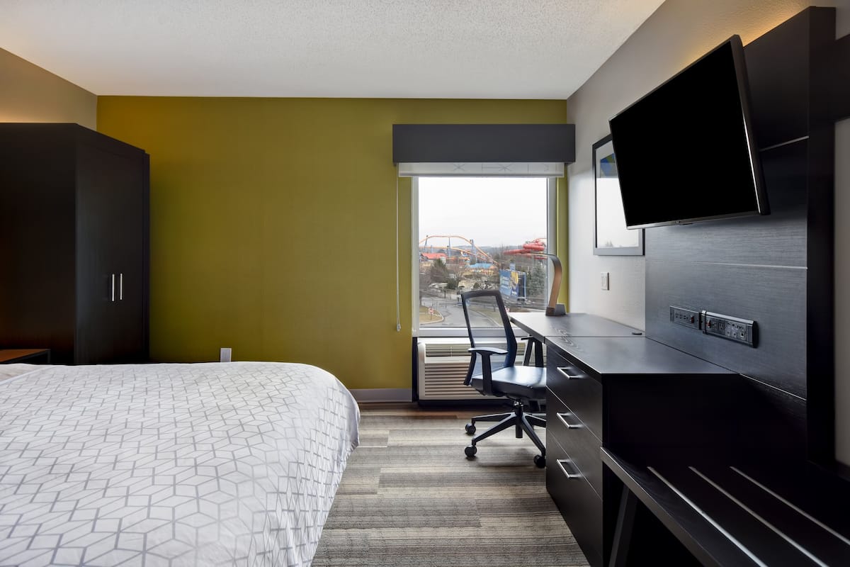 Hotelkamer met een bed, een bureau, een stoel, een televisie en een raam met uitzicht op de bouw.