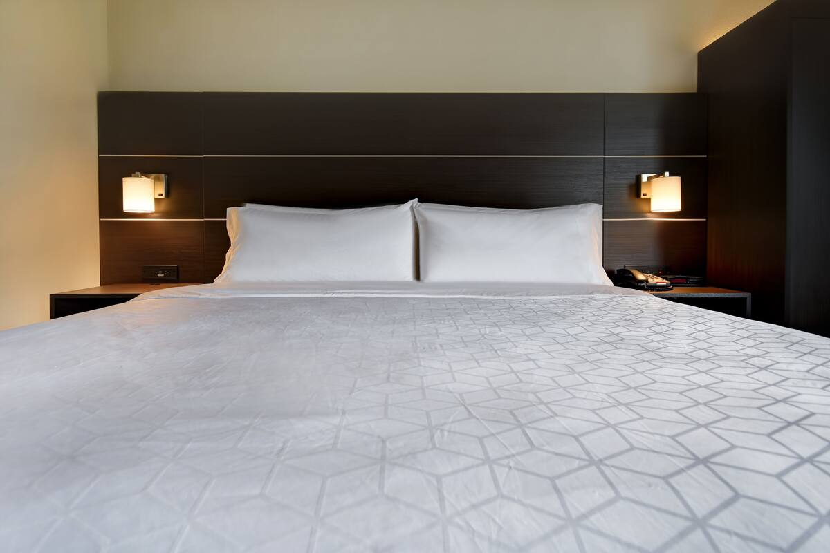 Een hotelkamer met een groot bed, twee nachtkastjes en wandlampen.