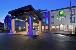 Ein Holiday Inn Express & Suites Gebäude mit überdachter Eingangspartei und einer gut beleuchteten Fassade.