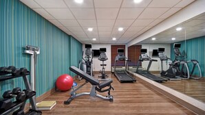 A gym with exercise equipment, a bench, and a red exercise ball.
