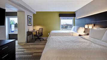 A hotel room with two beds, a desk, and a chair.