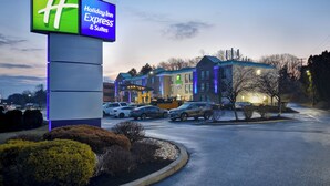 A Holiday Inn Express & Suites with a prominent sign, parking area, and buildings with a modern design.