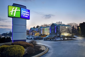 A Holiday Inn Express & Suites with a prominent sign, parking area, and buildings with a modern design.