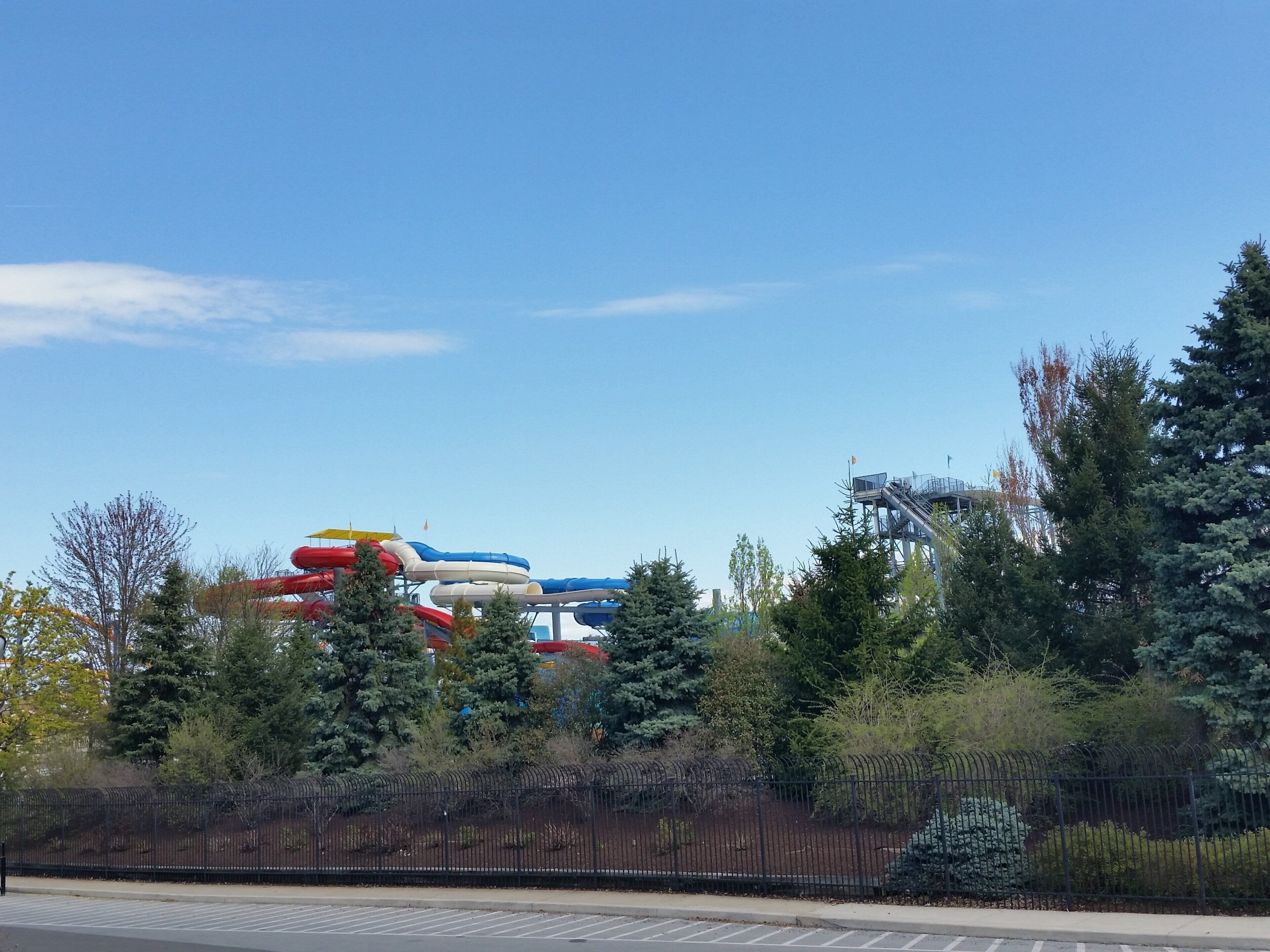 A water park with multiple water slides and a fenced area with trees.