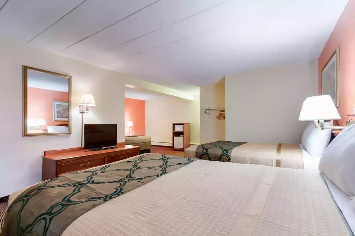 A hotel room with two beds, a television, a desk, and a lamp.