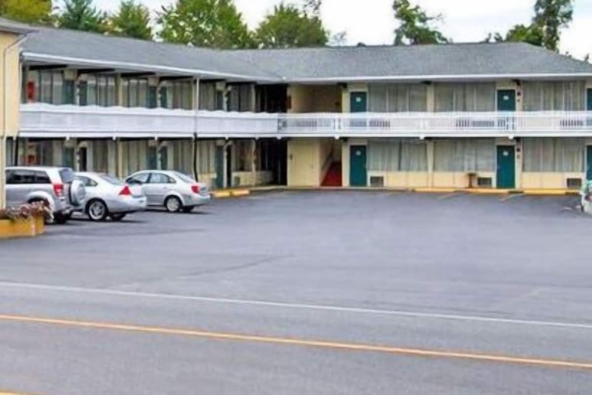 A motel with a two-story structure, a parking lot, and several cars parked in front.