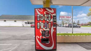 A Coca-Cola branded vending machine at a gas station with a Farm Table Restaurant sign in the background. - Royal Inn Clearfield (Clearfield)
