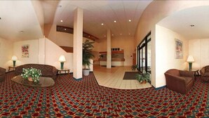 A spacious lobby with patterned carpet, two sofas, a coffee table, and a reception desk. - Suburban Studios Johnstown - Richland Town Center (Johnstown)