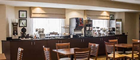 Un hall de hotel con mostrador de recepción, zona de estar y estación de café.