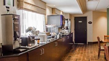 Una cocina de hotel con una máquina de café, estación de gofres y una vitrina de pastelería.