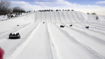Un paisaje nevado con varias pistas de trineo y gente deslizándose por las laderas.