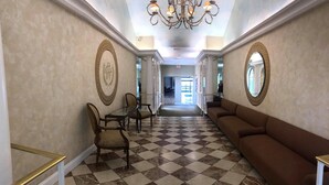 A hallway with a checkered floor, a sofa, a table with chairs, and two ornate wall decorations. - Heritage Hills Golf Resort (York)
