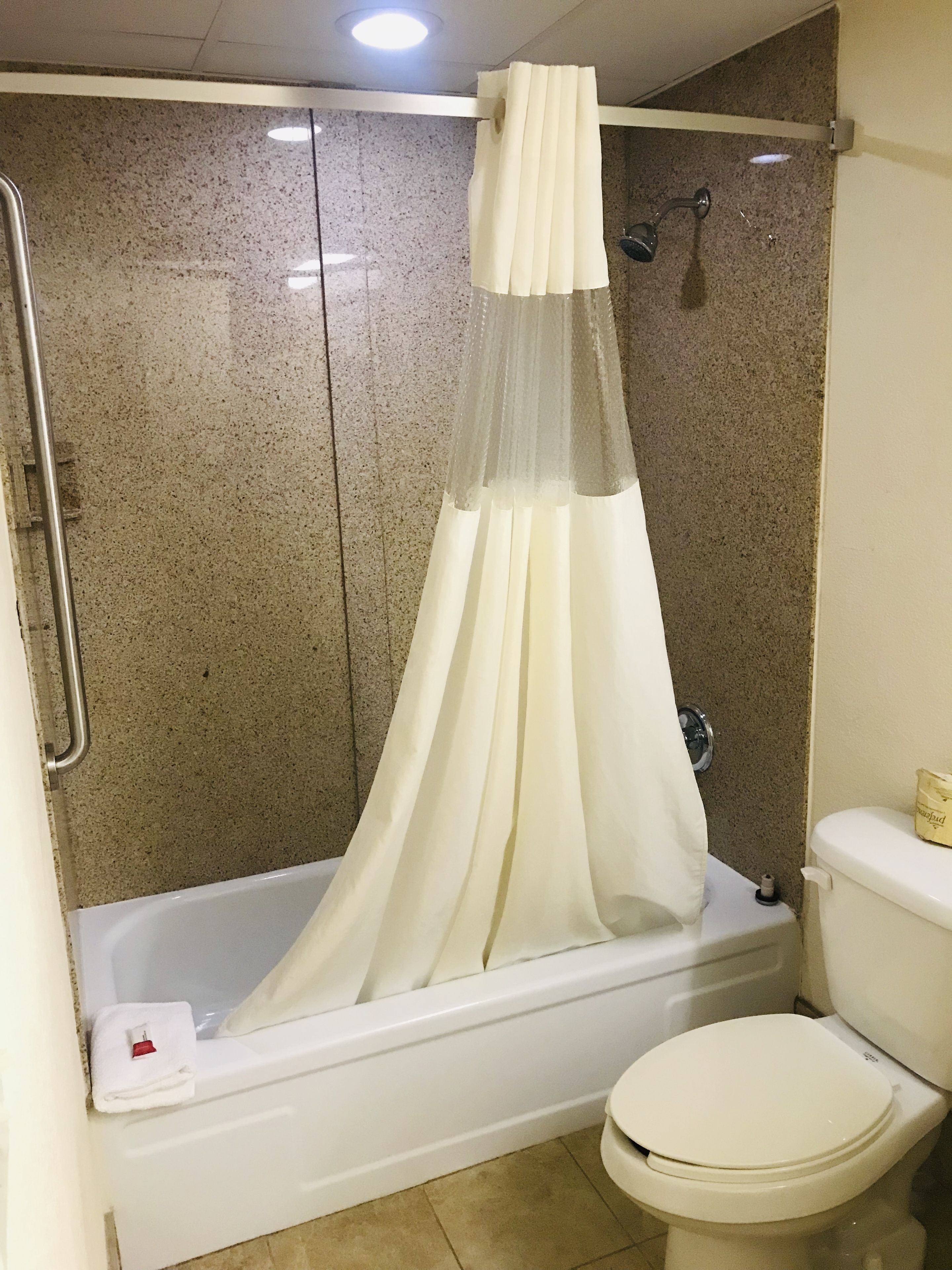 Un baño con bañera, inodoro y cortina de ducha.