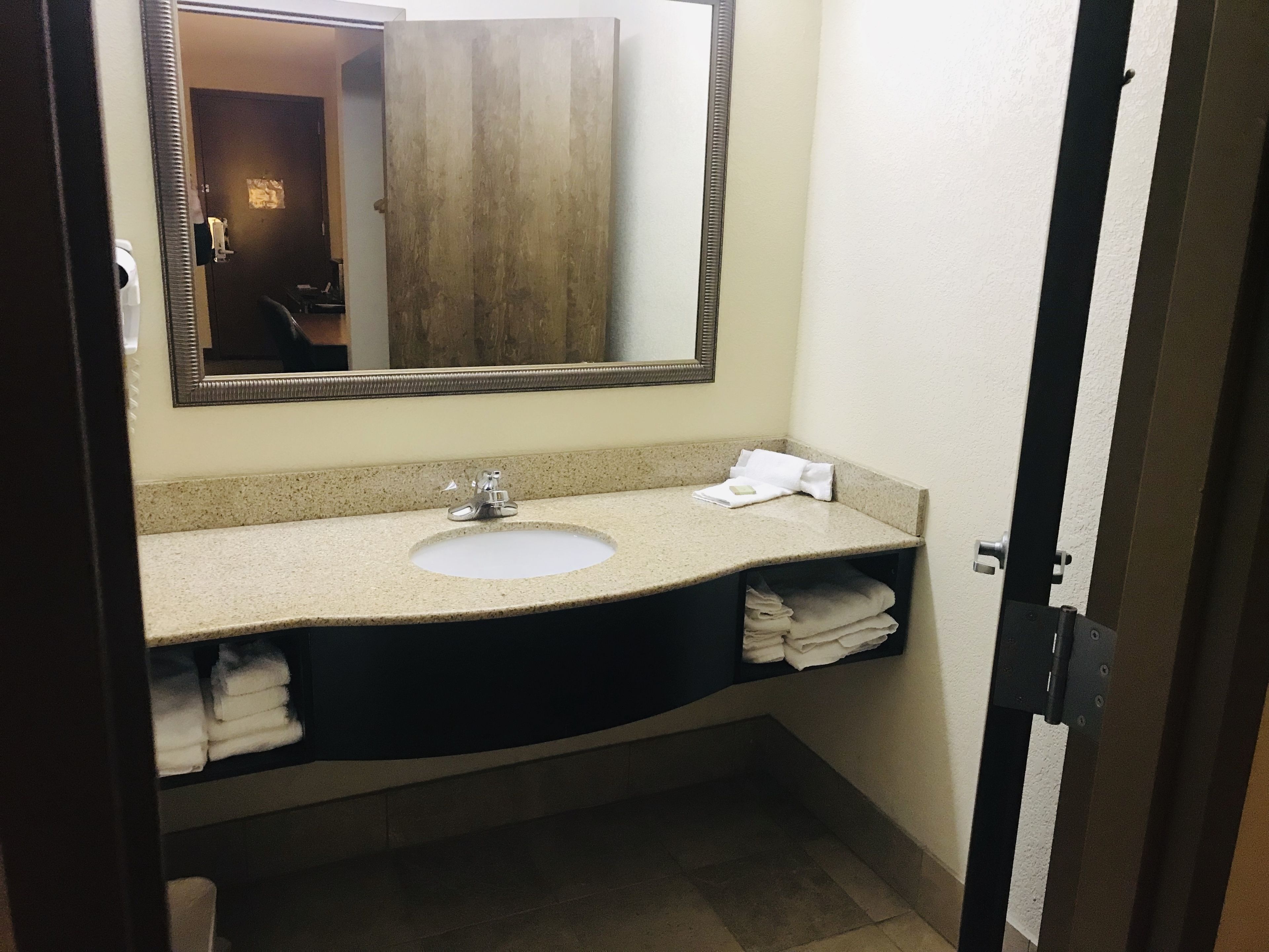 Un baño con lavabo, espejo y perchero para toallas.
