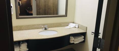 Un baño con lavabo, espejo y perchero para toallas.
