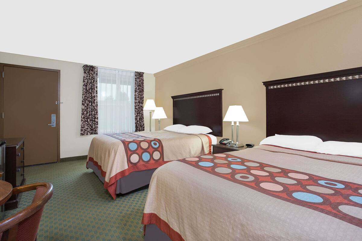 Een hotelkamer met twee bedden, een bureau en een stoel.