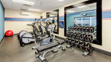 Una palestra con tapis roulant, ellittiche e un espositore per manubri.