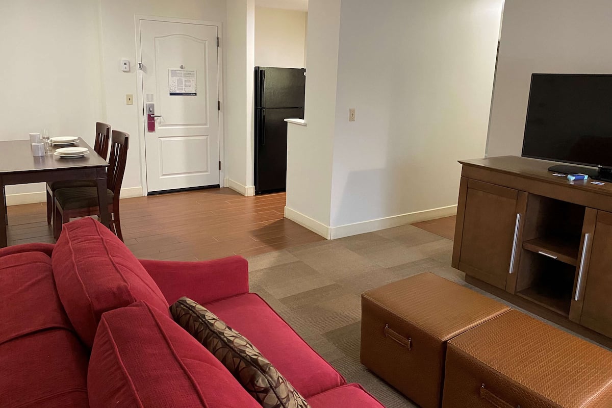 A living room with a red sofa, a wooden cabinet, and a television on a stand.